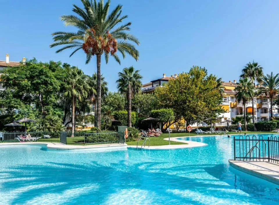 Piscina azul entre palmeras en la urbanización